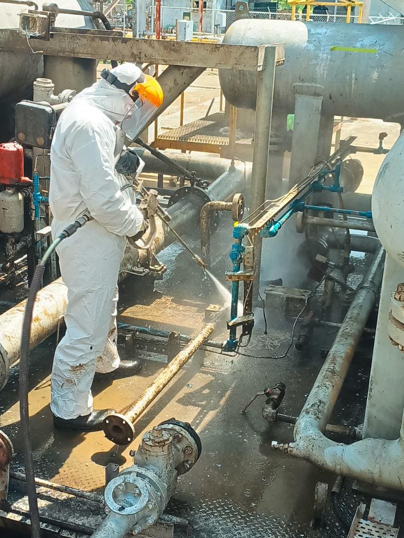 Técnico con traje Tyvek y careta realizando hidrolavado industrial